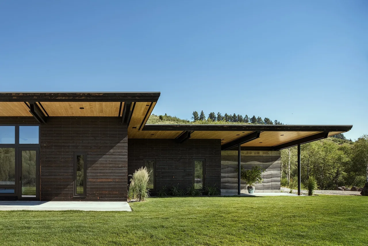 Exterior view of the Freedom Residence showing dark wood siding and a cantilevered flat roof overhang.