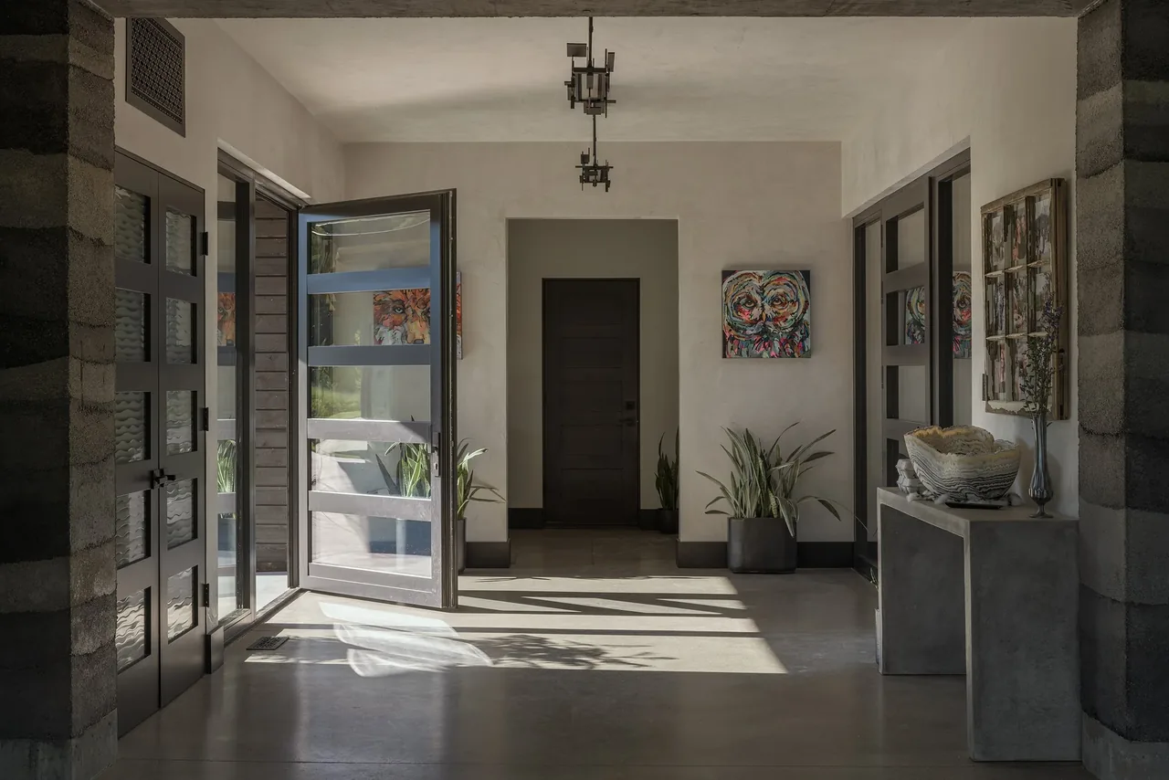 Entry space features concrete floors, a pivot door with horizontal glazing, and modern minimalist decor.