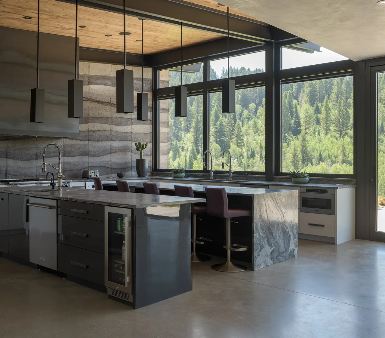Kitchen features a large marble island, floor-to-ceiling windows, and a concrete floor.