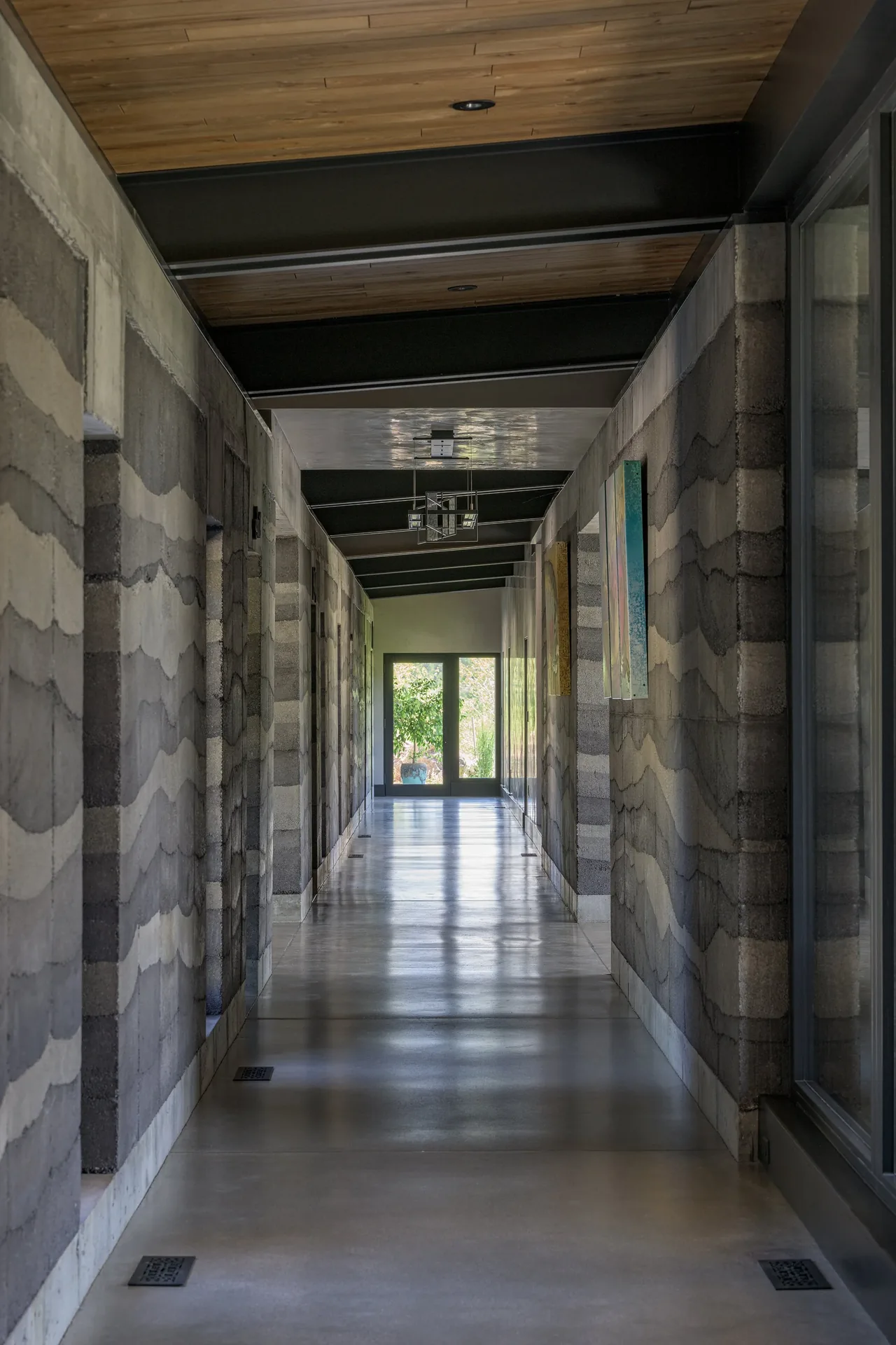 Interior view of a long hallway with concrete block masonry walls and polished concrete flooring