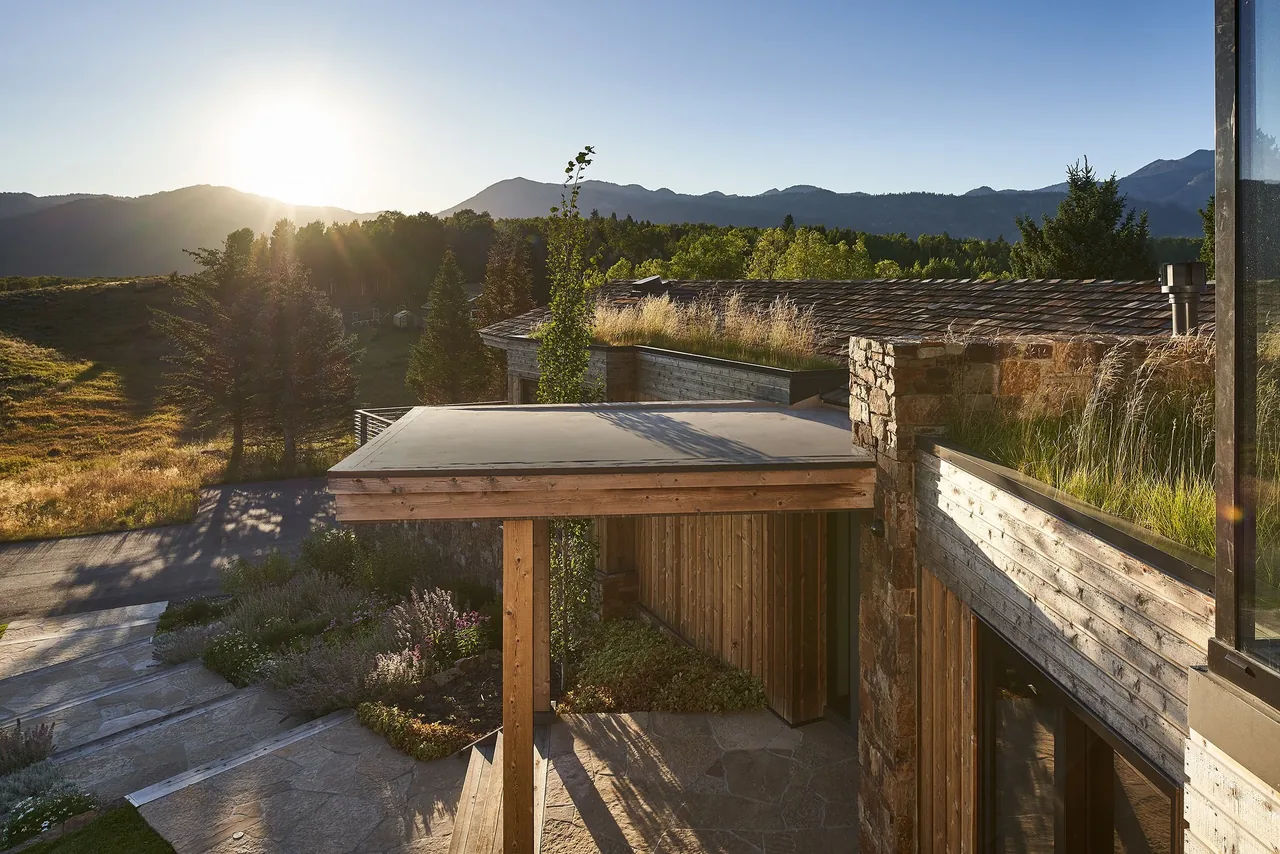 Skyline Ranch Residence features a flat roof, wood siding, and integrated grassy roof elements with mountain views.