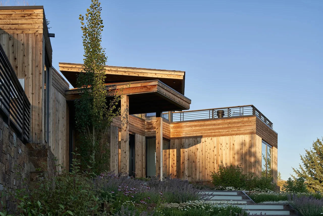 Skyline Ranch Residence features multi-level wood siding, large windows, and a covered entry with a metal railing on the upper deck.