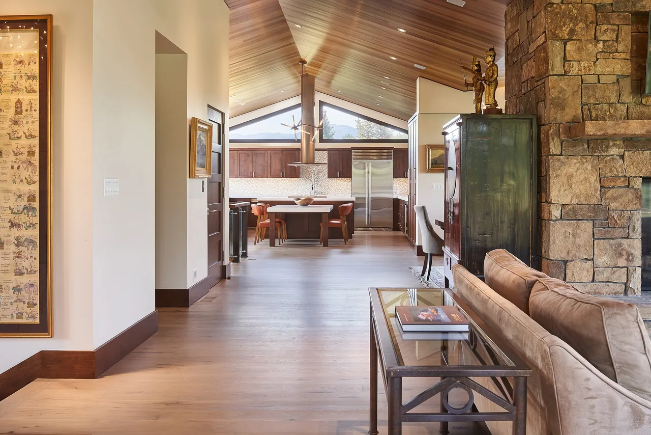 Living room opens to kitchen with vaulted wood-paneled ceiling and large triangular windows at Skyline Ranch Residence.