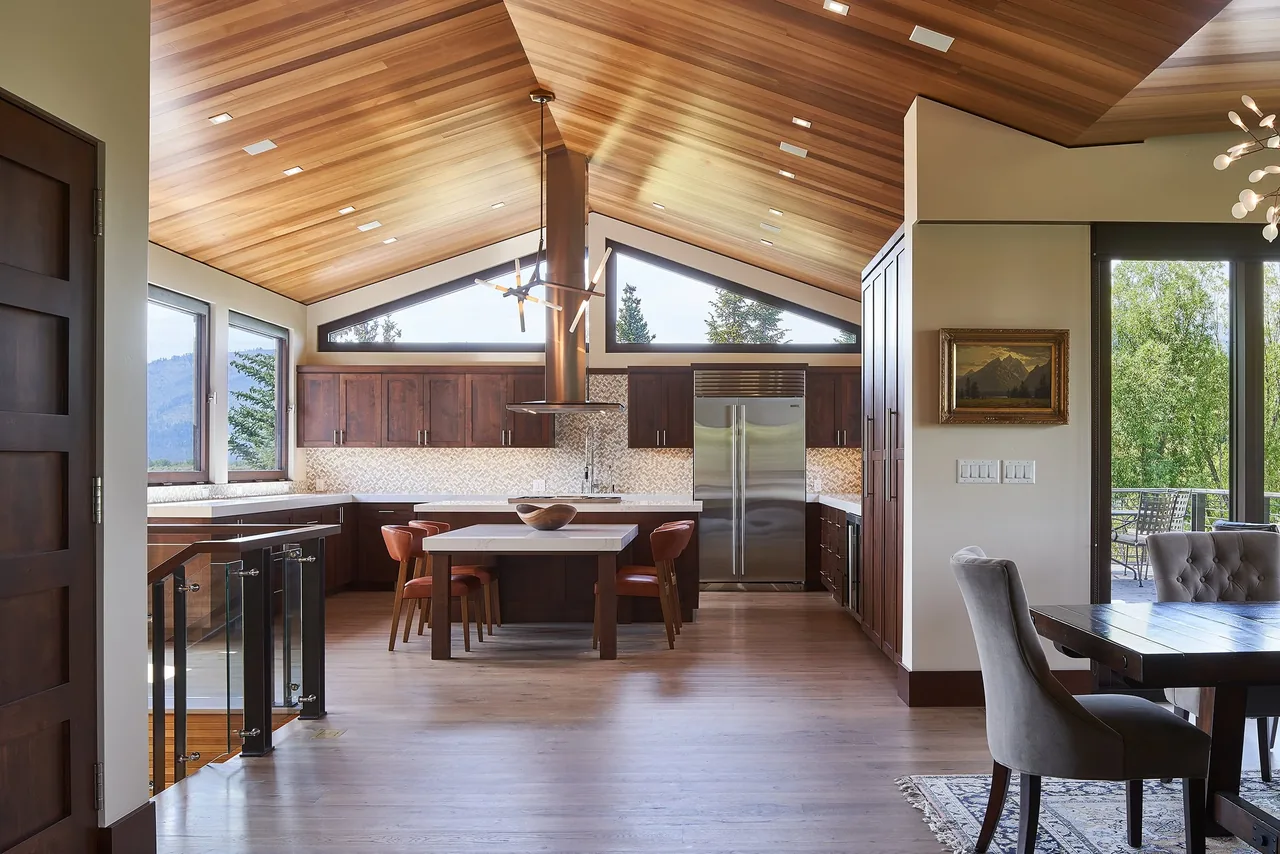 Kitchen with vaulted wood ceiling, dark wood cabinets, and triangular clerestory windows overlooking trees and mountains.