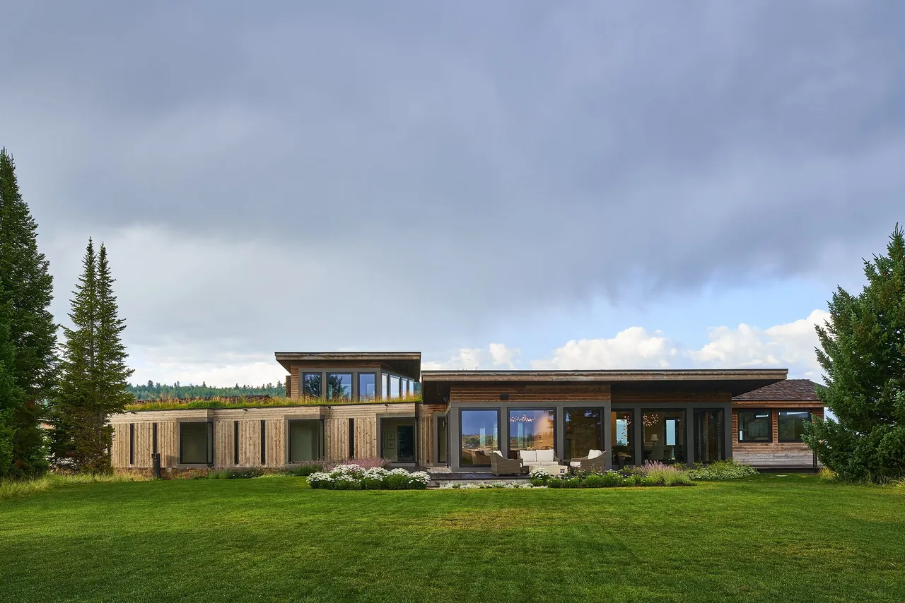 Skyline Ranch Residence features a multi-level design with large windows and wood siding in a grassy landscape.