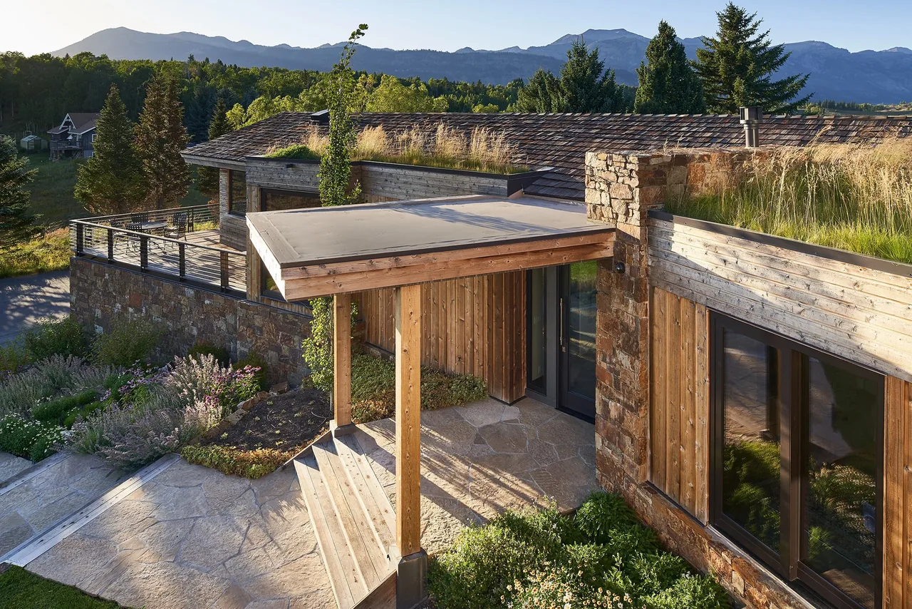 Skyline Ranch Residence features wood and stone exterior, flat roof with green roof planting, and large windows overlooking mountains.