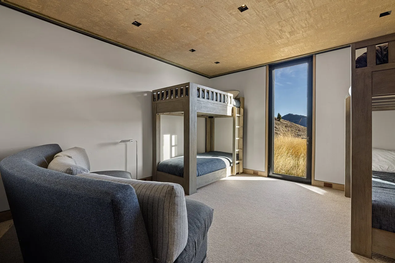 Interior view of a bedroom with bunk beds and a floor-to-ceiling glass door providing natural light and outdoor views.
