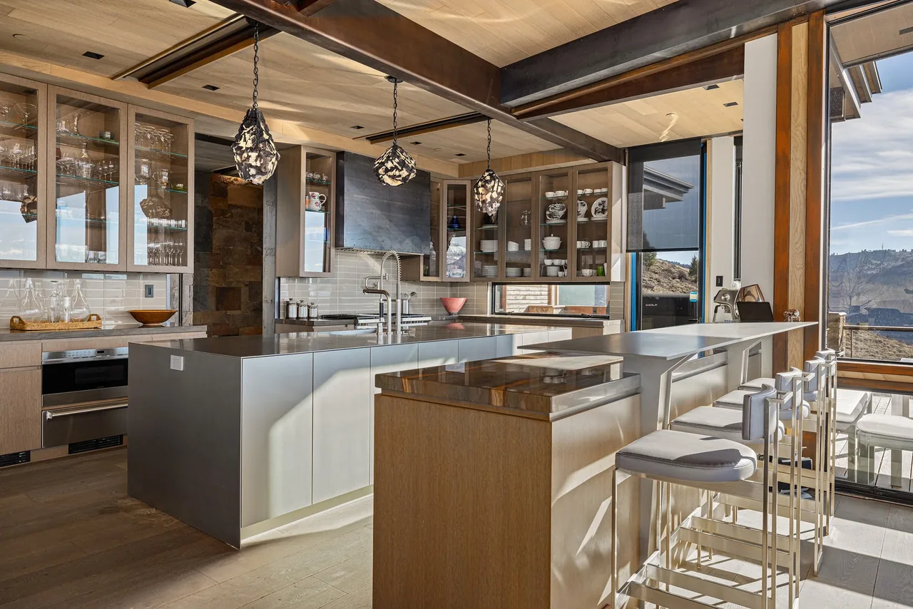 Kitchen with wood and metal finishes, glass-front cabinets, and pendant lighting.