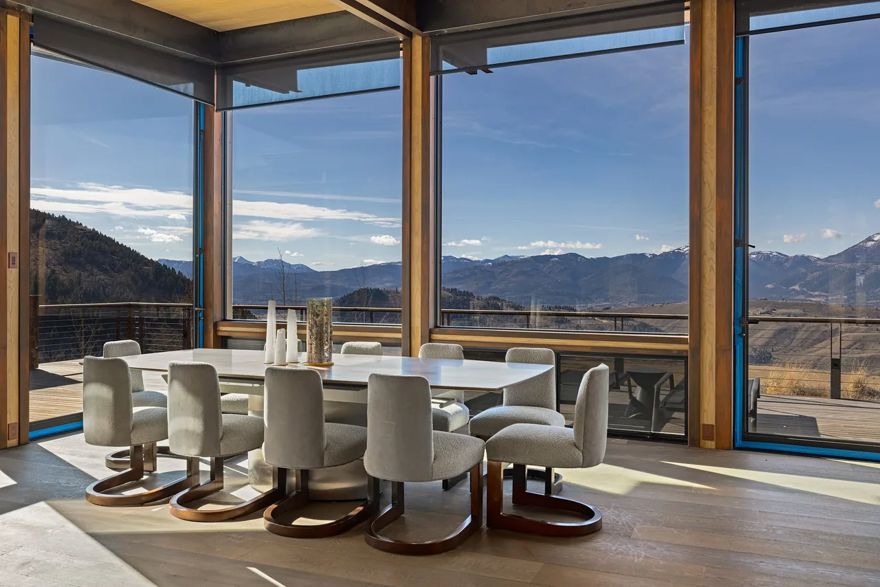 Dining area with floor-to-ceiling glass windows offering a panoramic mountain view.