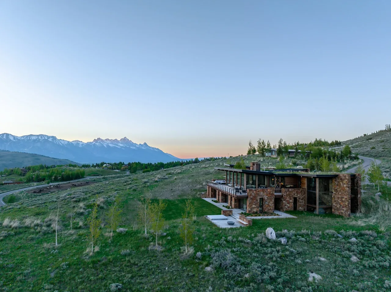 The Ridge 52 Residence features a stone facade and expansive terraces overlooking a mountainous landscape.