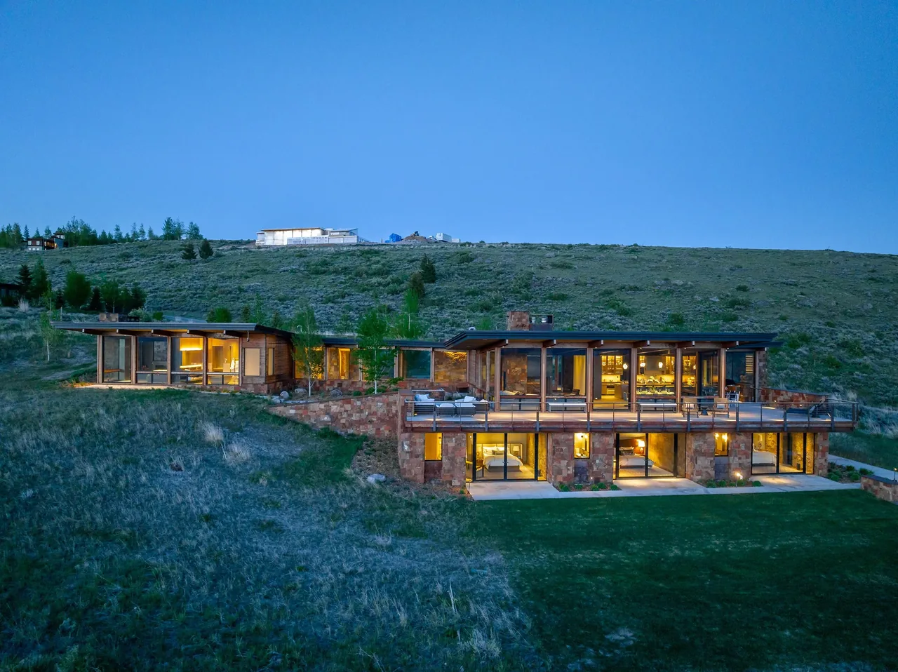 The Ridge 52 Residence features a two-level design with glass walls and stone cladding on a sloped site.