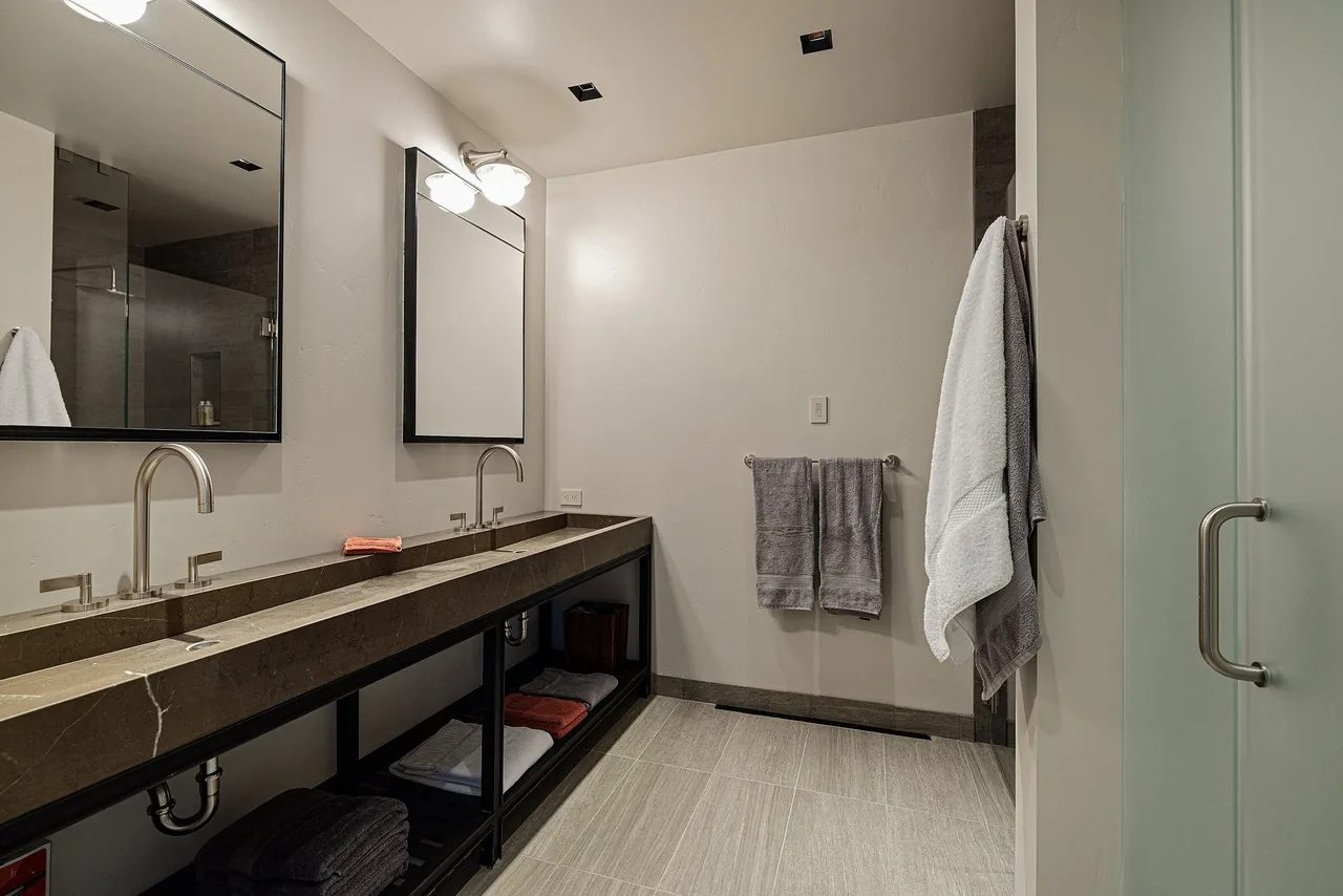 Bathroom features a double undermount sink with stone countertop and two framed mirrors.