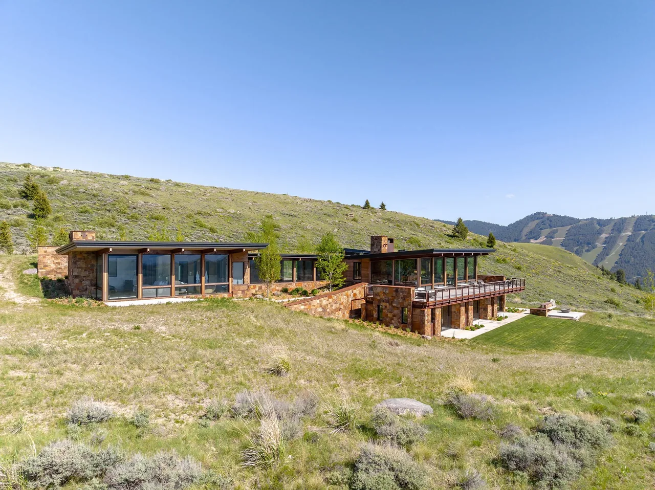 The Ridge 52 Residence features a hillside layout with stone facade and floor-to-ceiling glass windows under flat roofs.