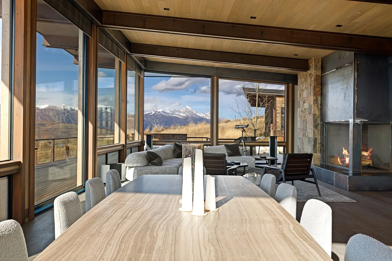 Open dining and living area featuring floor-to-ceiling glass windows and a corner fireplace.