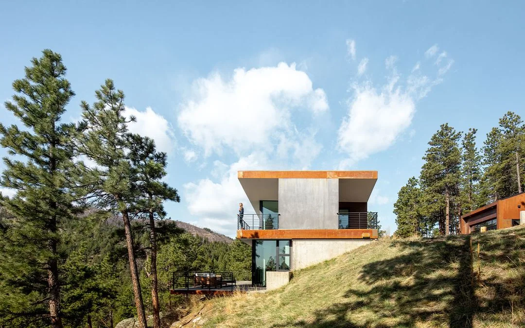 Puma Run features a modern home with a covered patio and metal railing overlooking a forested mountain landscape.