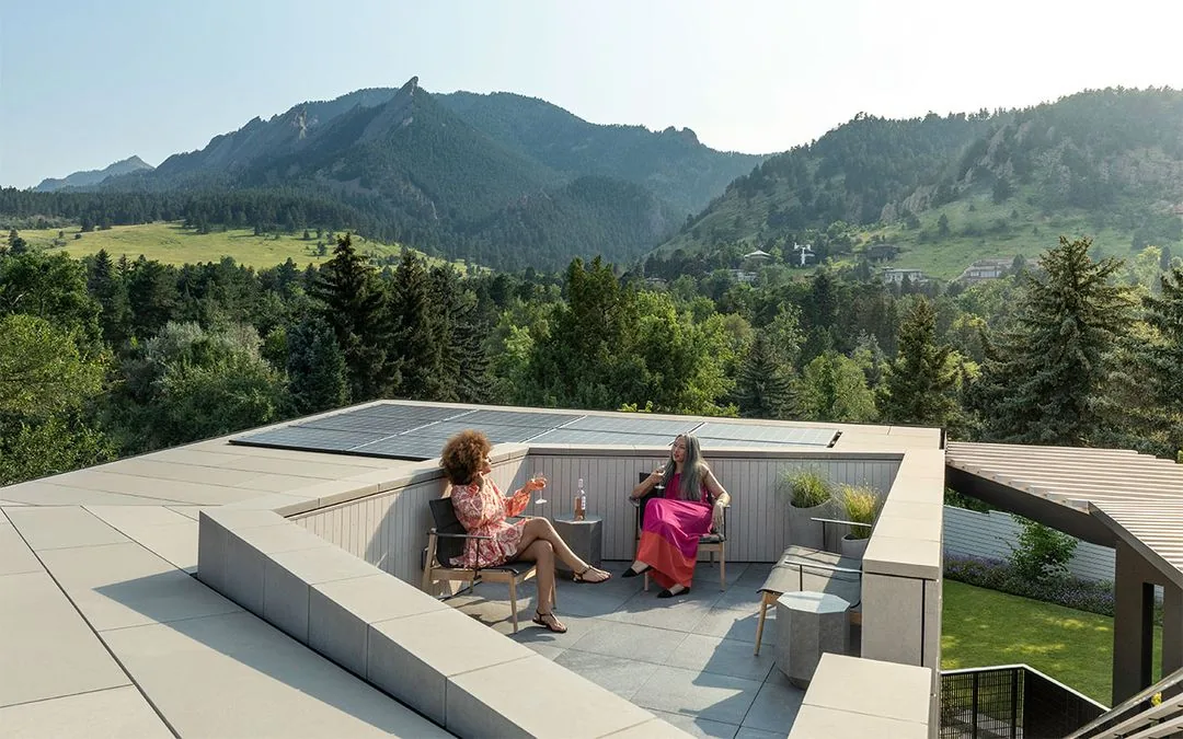 Recessed rooftop patio of Vergence House with seating and solar panels visible on flat roof.