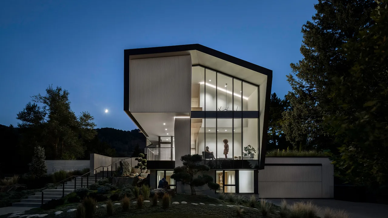 Night exterior view of Vergence House showcasing floor-to-ceiling glass and angular roof design.
