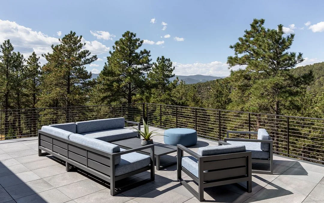 Rooftop patio features modern outdoor furniture and overlooks a wooded landscape.
