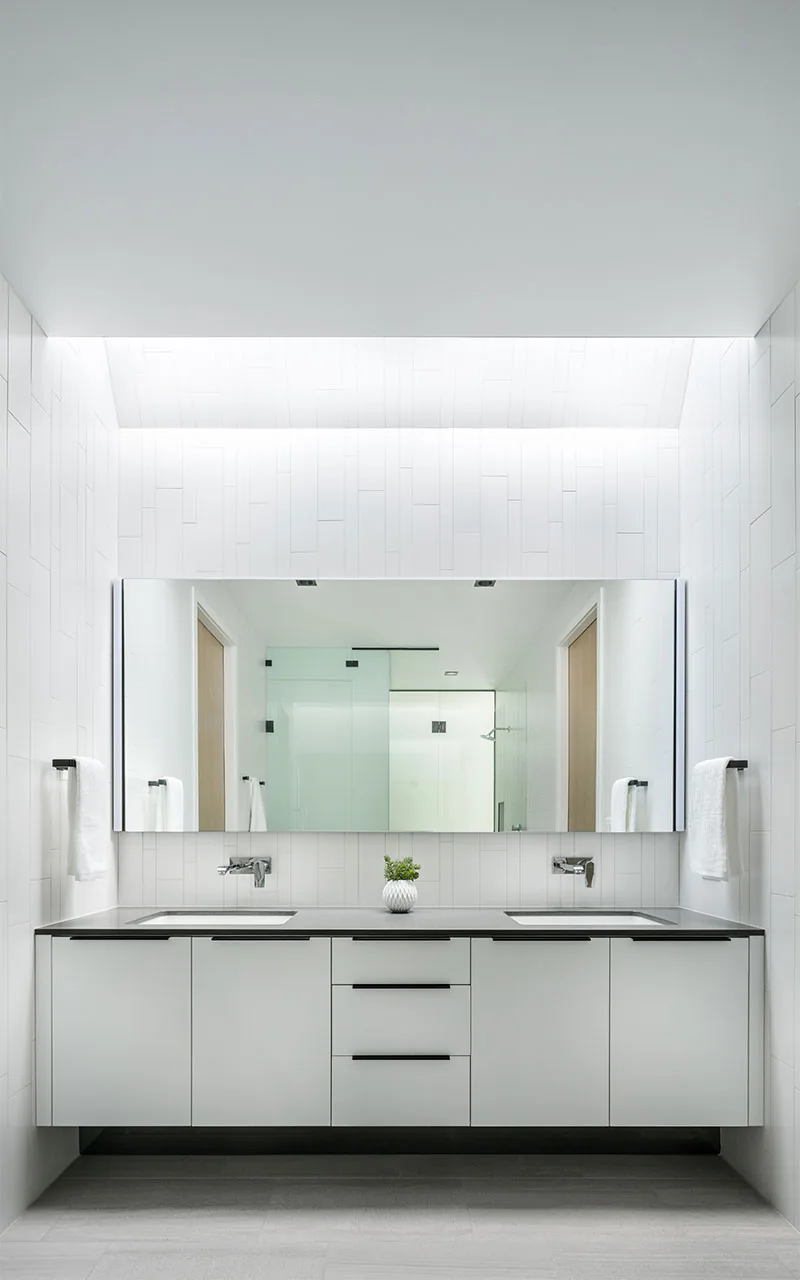 Minimalist bathroom featuring a floating double vanity, large horizontal mirror, and backlighting above.