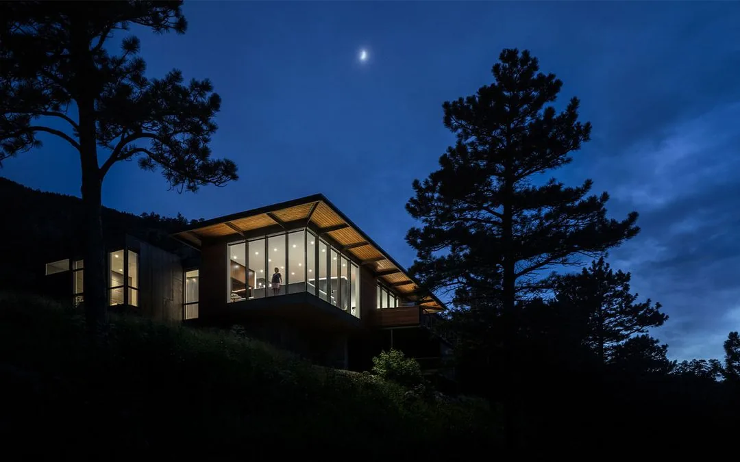 Night exterior view of House 306 featuring floor-to-ceiling glazing and an overhanging flat roof.