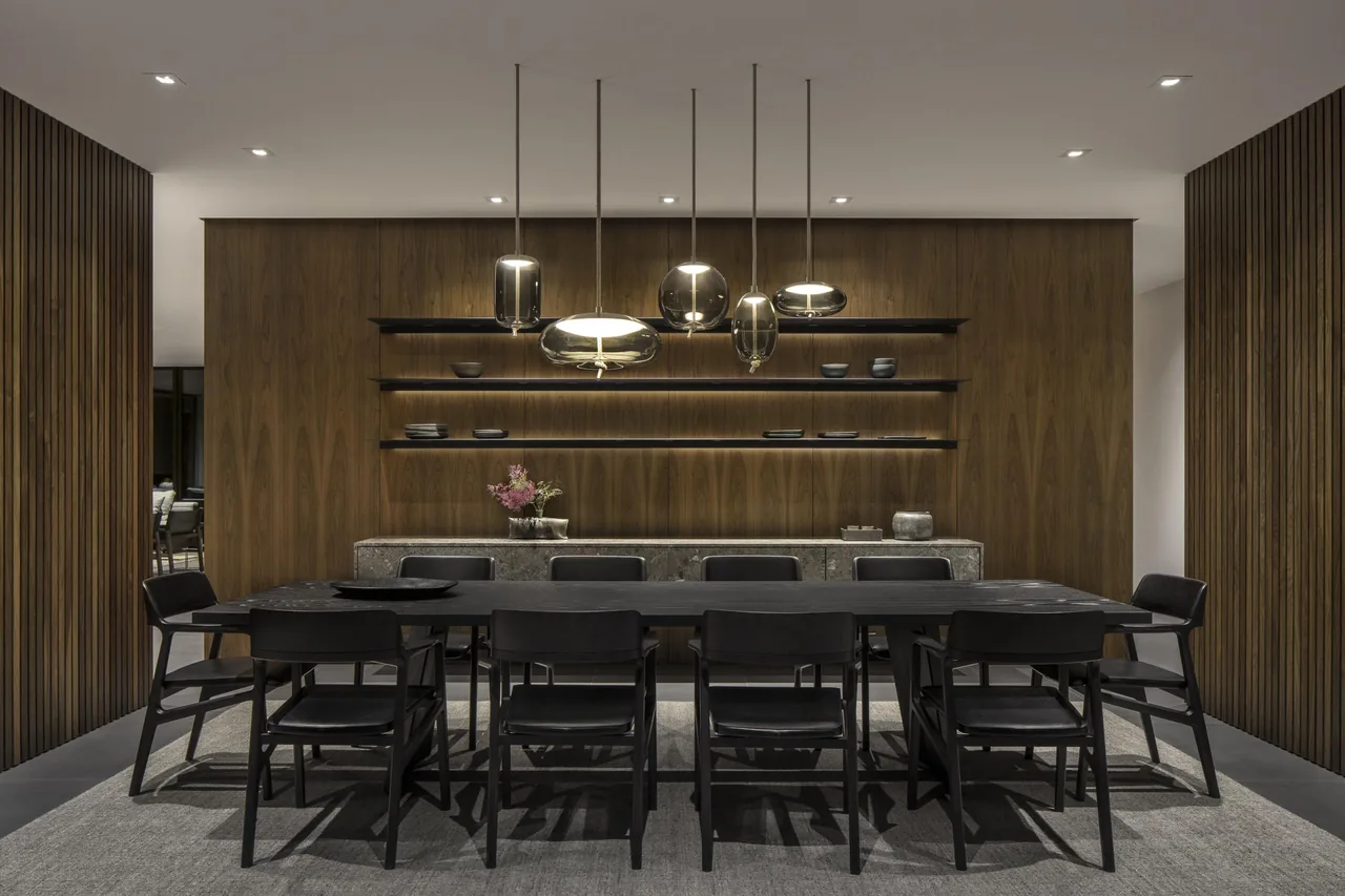 Dining room with black furniture and wood-paneled wall with floating shelves.