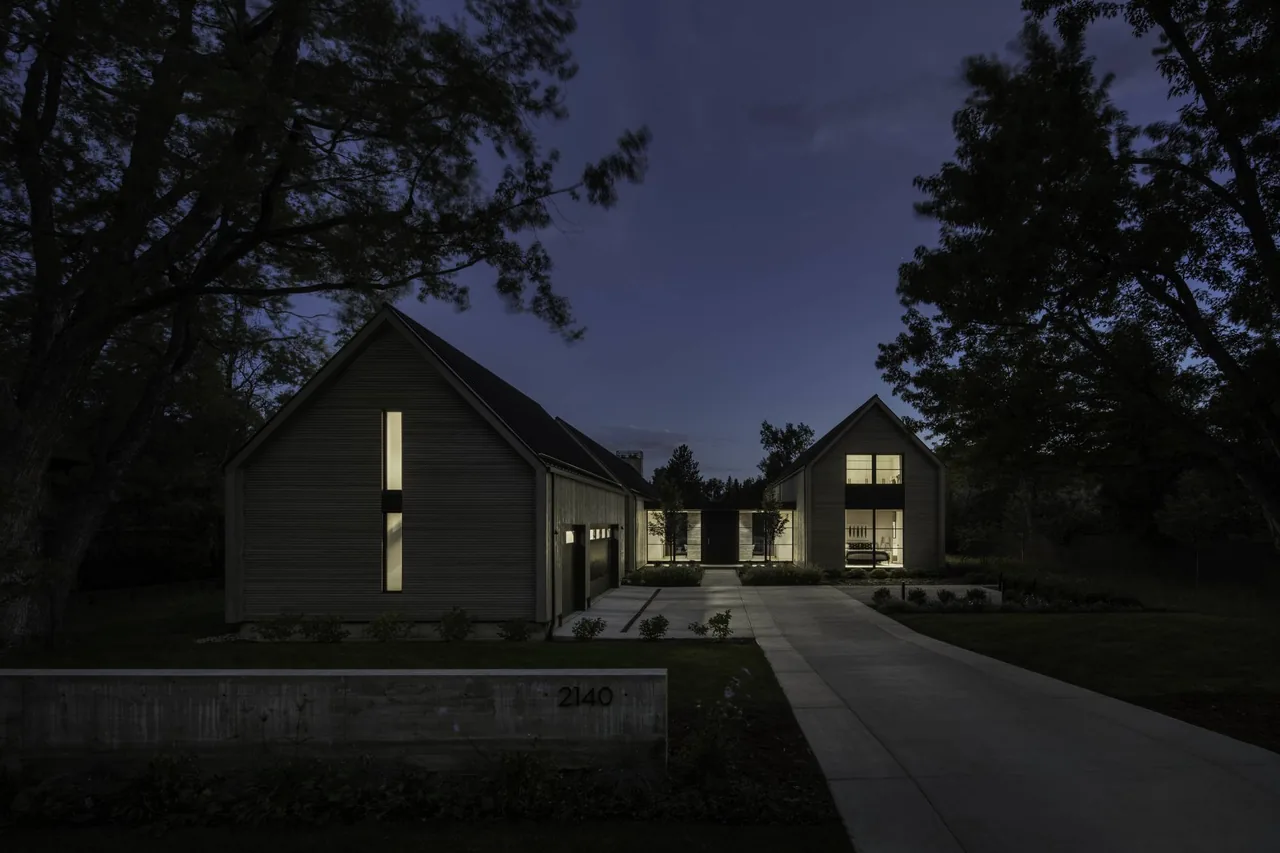 Linden Grove features modern architecture with vertical siding and illuminated windows, framed by symmetrical trees at night.