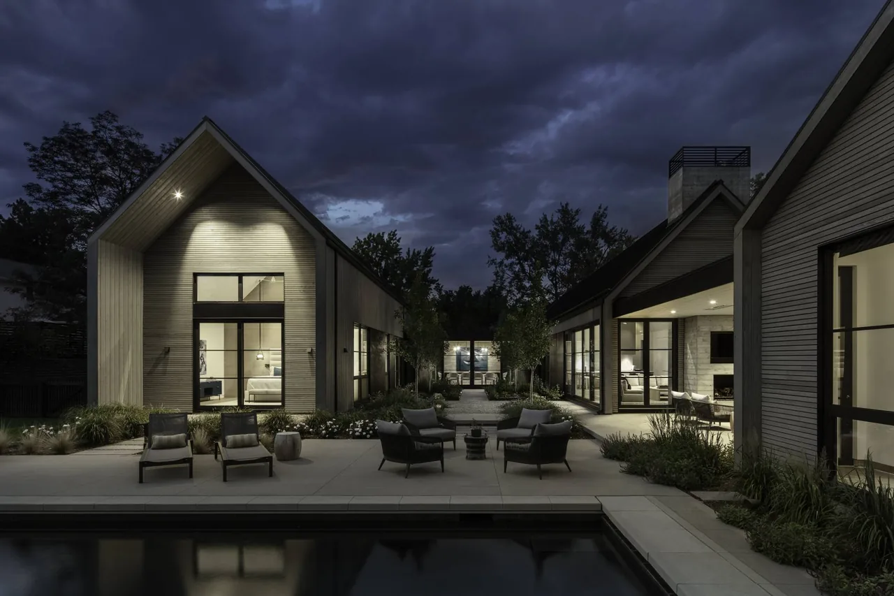The Linden Grove project features a wood-paneled exterior with large glass windows surrounding a courtyard and pool area at night.
