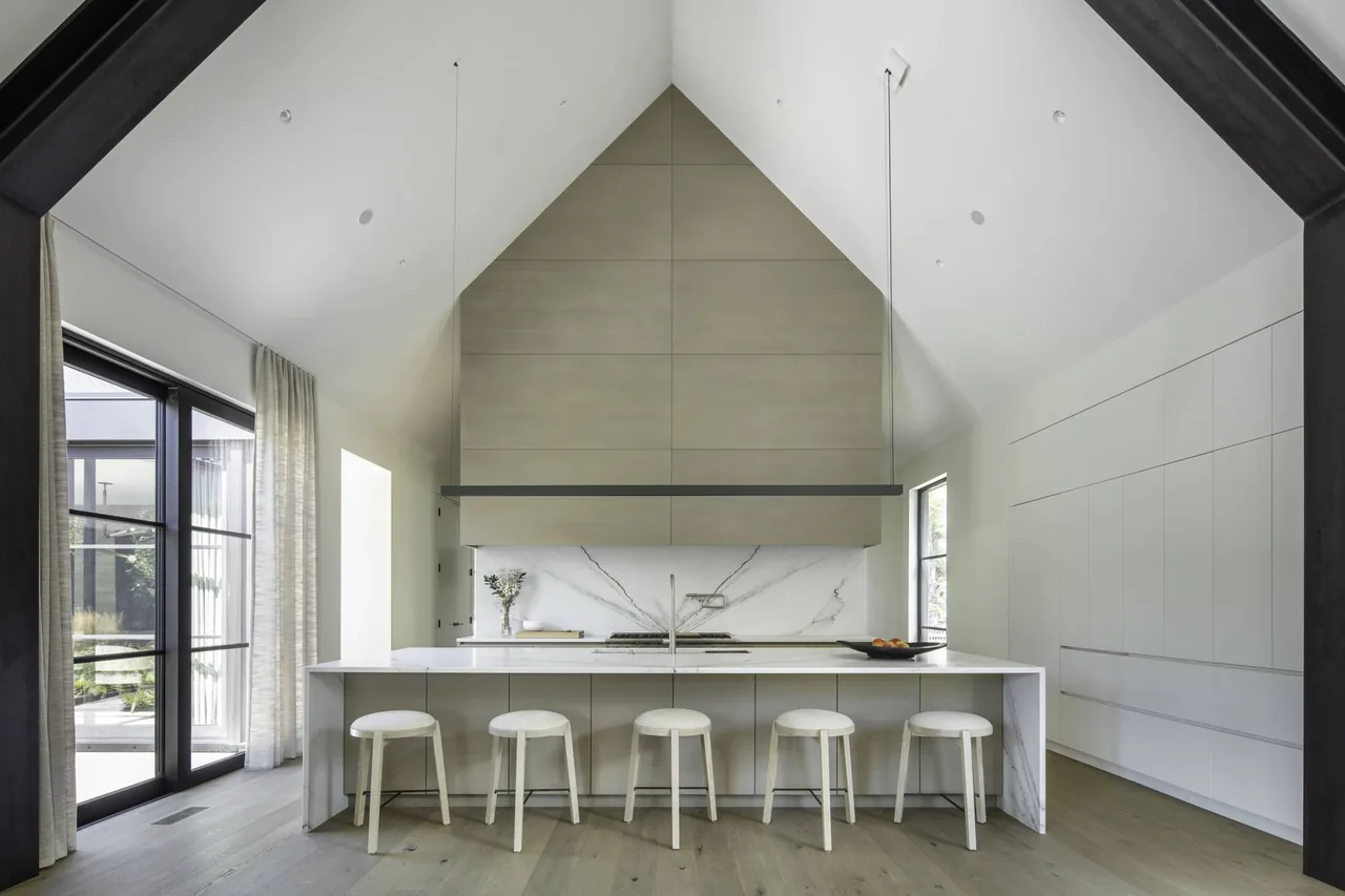 Vaulted ceiling kitchen with minimalist cabinetry and large island seating five stools.