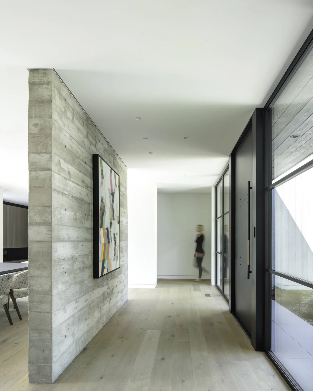 Hallway with exposed concrete wall and floor-to-ceiling glazing at Linden Grove project by Studio B Architects