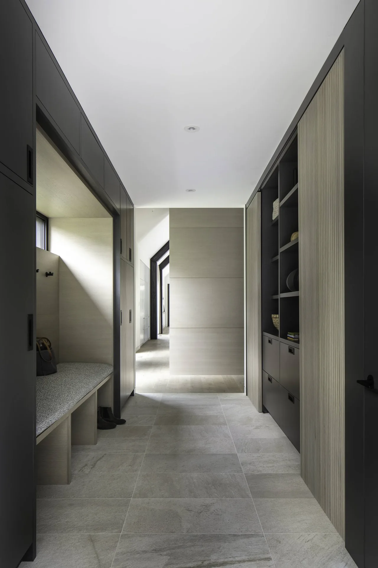 Hallway in Linden Grove with built-in bench, cabinetry, and stone tile flooring by Studio B Architects.