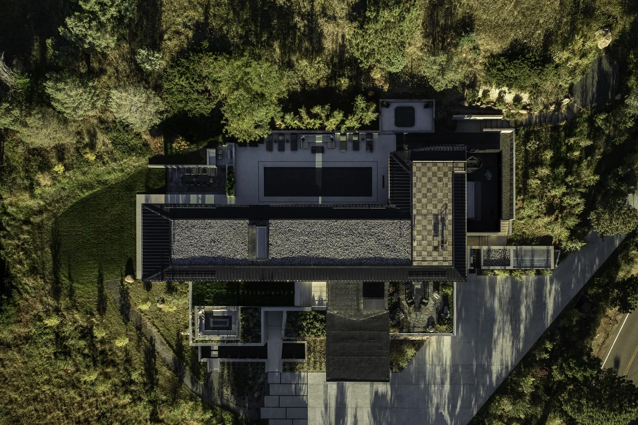 Aerial view of Panorama House featuring a flat roof, pool, and landscaped outdoor areas near a road.