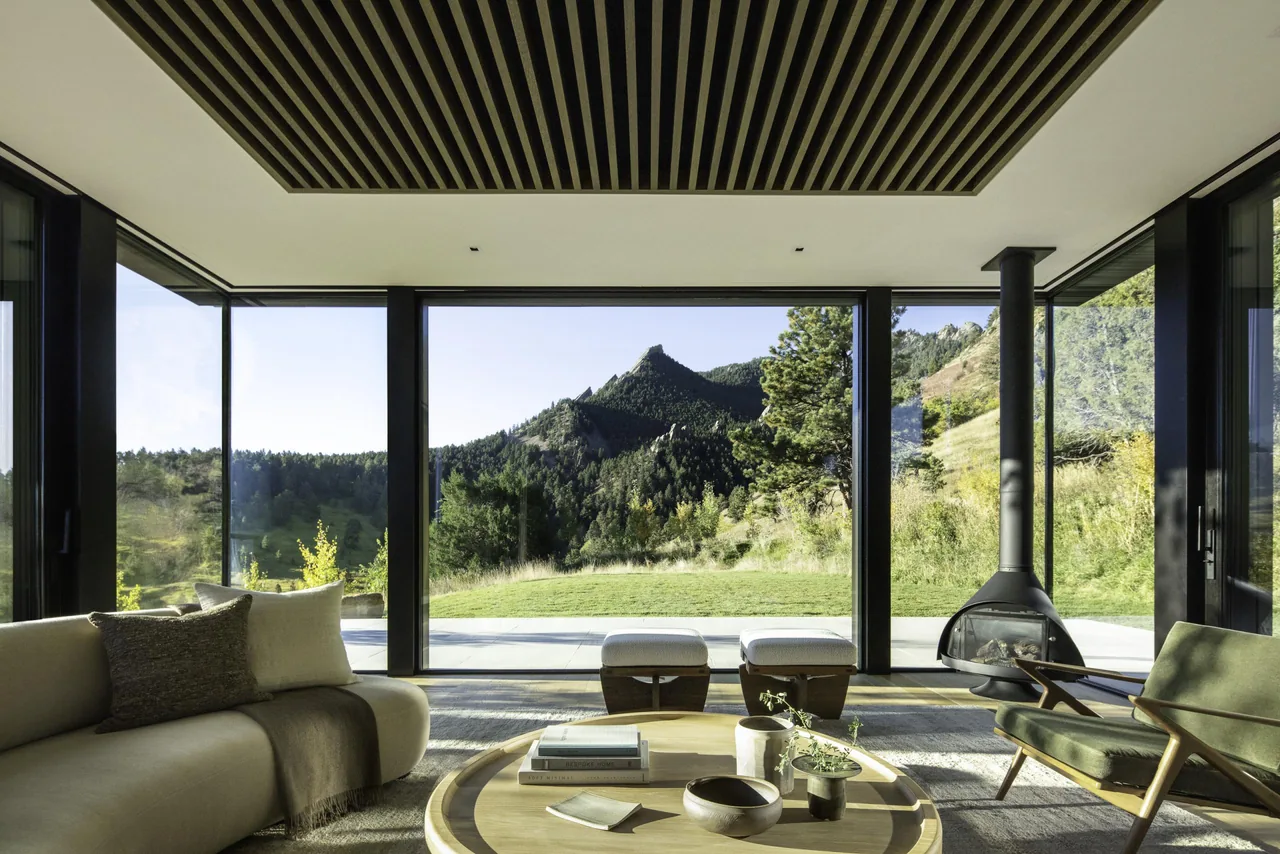 Living room with floor-to-ceiling glazing framing a mountainous landscape.
