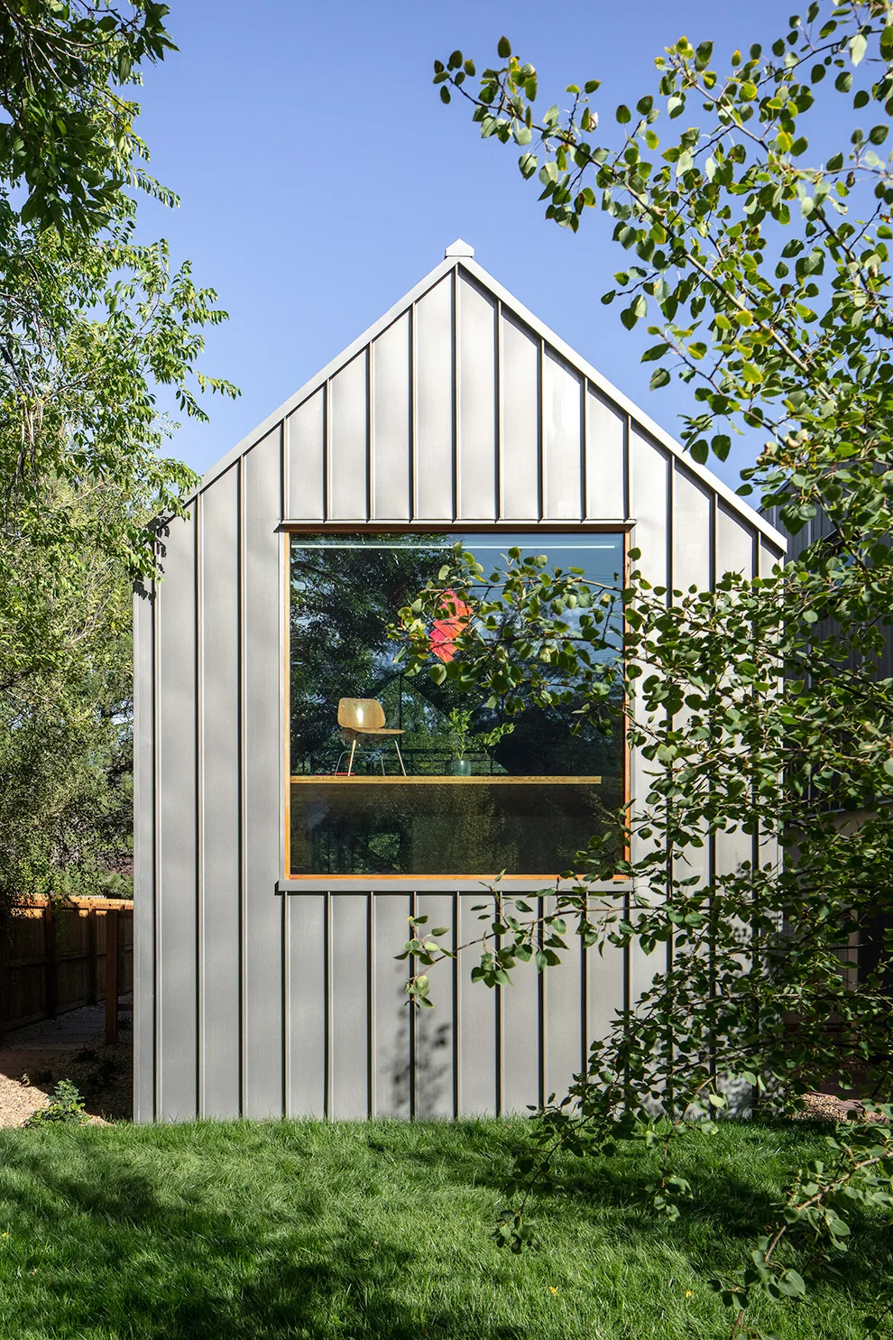 Gable end of a small building featuring vertical metal siding and a large wood-framed picture window.