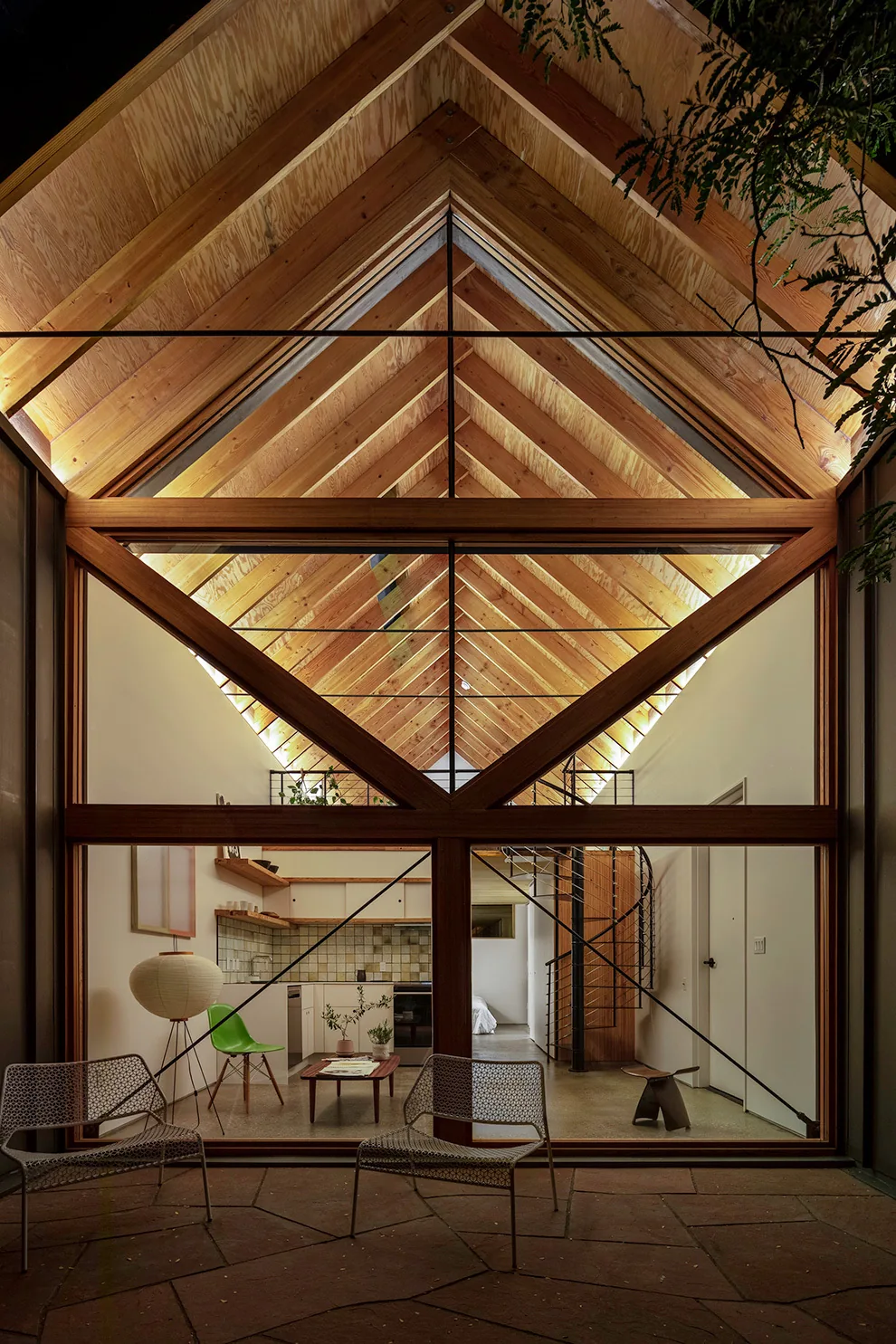 Interior shot of an A.D.U. showing exposed wood vaulted ceiling and kitchen with tiled backsplash at night.