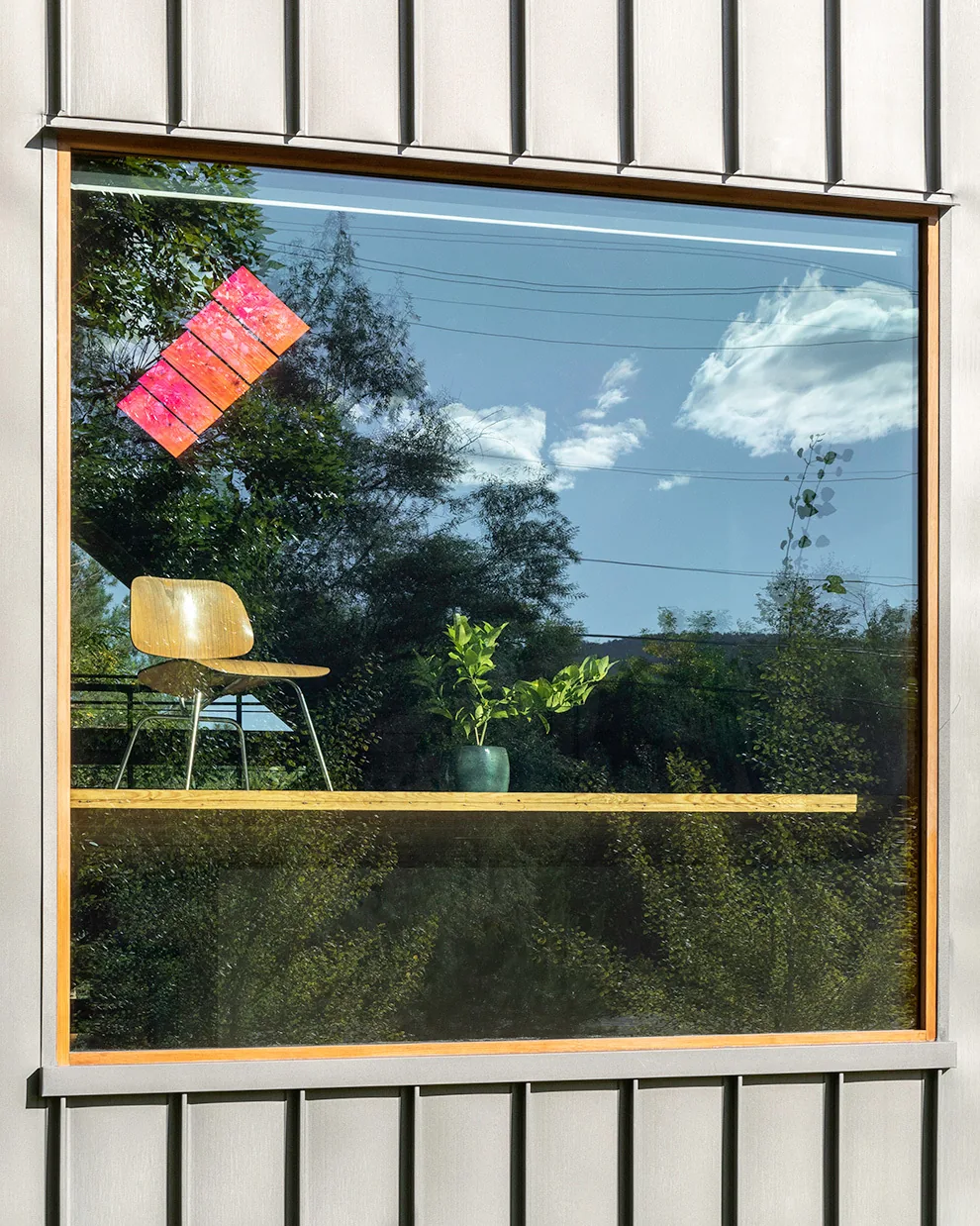 Exterior view of a large square window with wood trim set in vertical metal siding on an A.D.U. project.