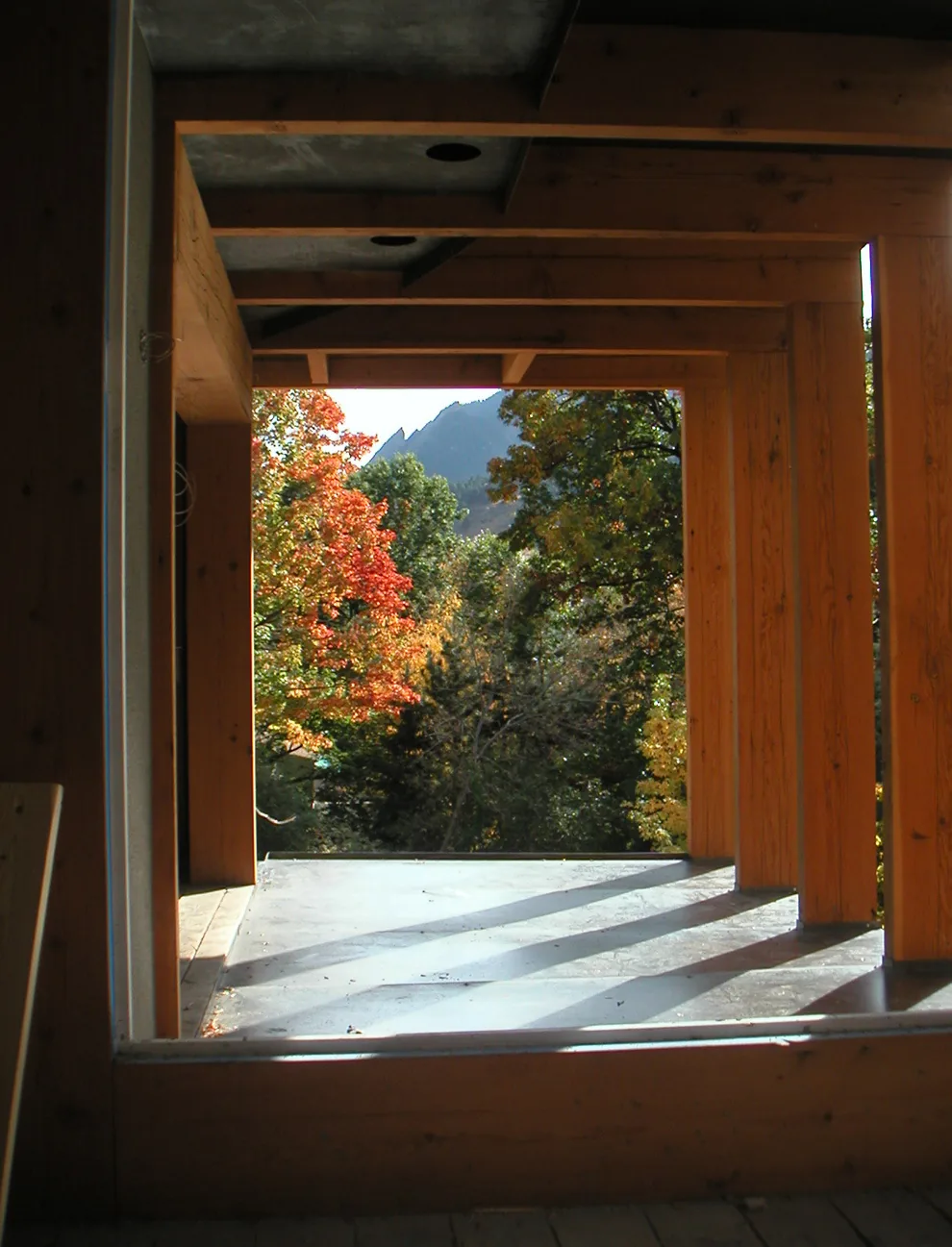 Open porch framed by exposed wooden beams facing a view of colorful autumn trees and mountains.