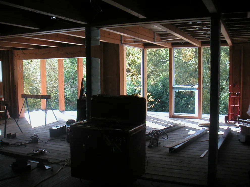 An interior under construction showing exposed wood framing and window openings with natural light.