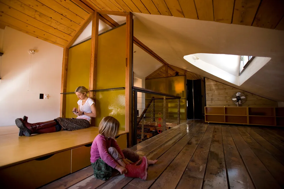 Upper floor room with wood plank floors, sloped ceiling with skylight, built-in bench seating, and cable railing stair barrier.