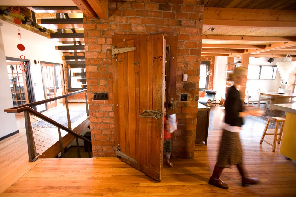 Interior features a combination of exposed brick, wooden floors, rustic wooden door, and visible structural beams.
