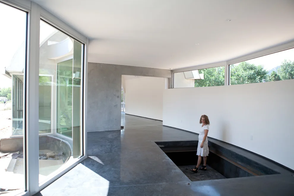 Modern interior space with polished concrete floors, floor-to-ceiling glazing, and a sunken seating area.
