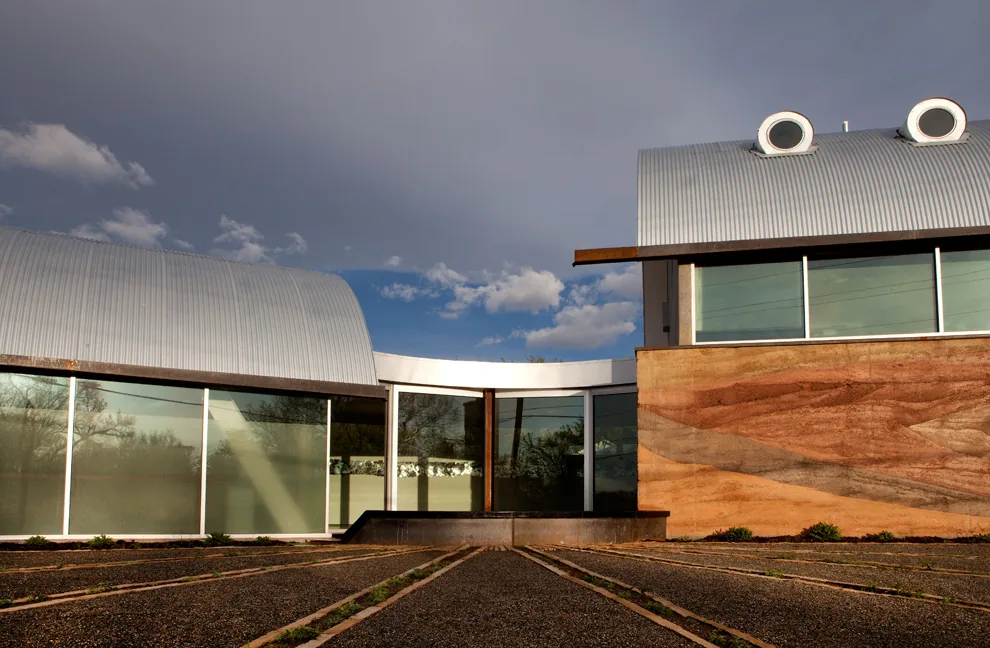 Modern building exterior featuring curved metal roofs and rammed earth walls.