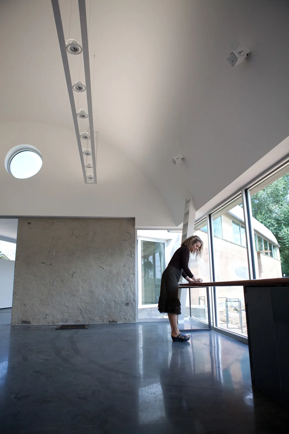 Interior of a modern space featuring polished concrete floors, a concrete accent wall, and a large glass window wall with a wooden counter.