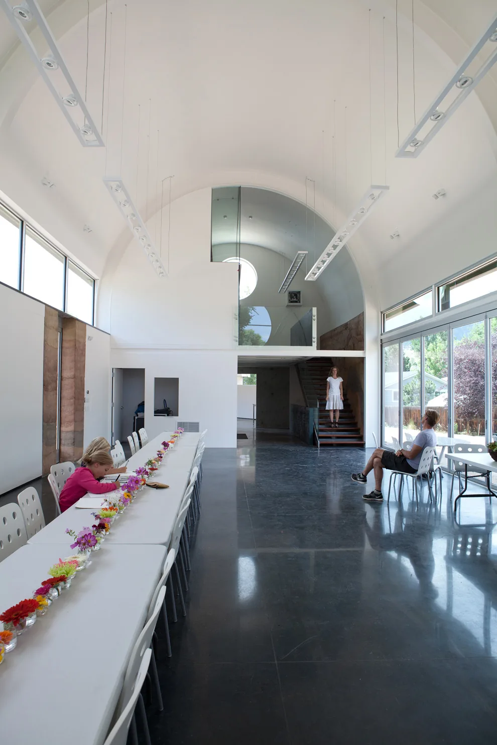 Interior of a dining area with vaulted ceilings, long table, and large windows providing natural light.