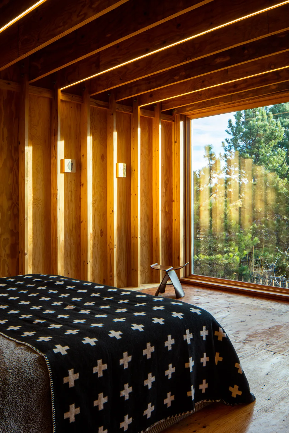 Bedroom interior featuring exposed wood framing and a large picture window.