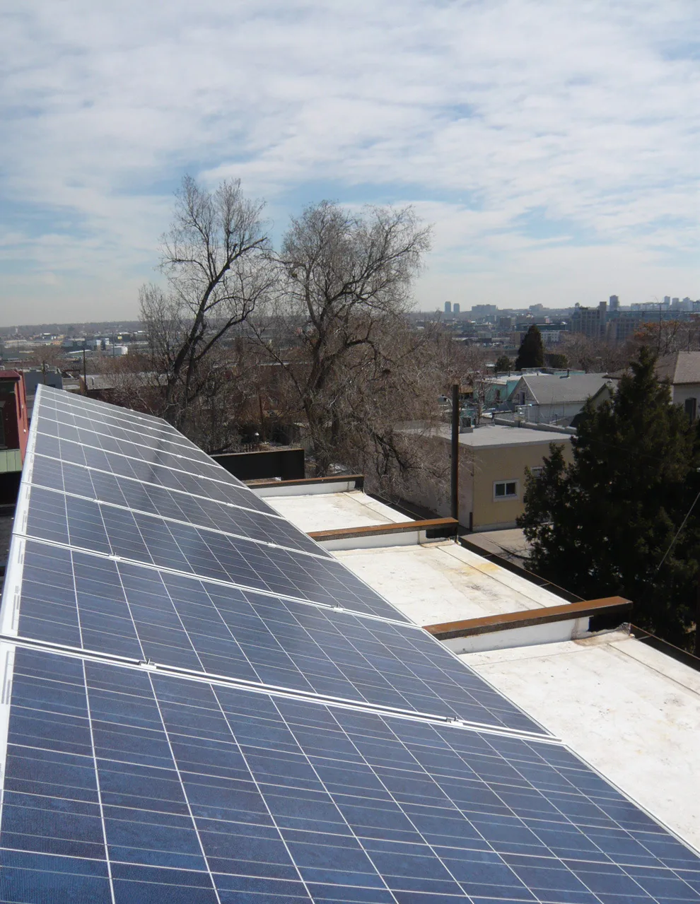 Solar panels mounted on the flat roof of a building in an urban setting.