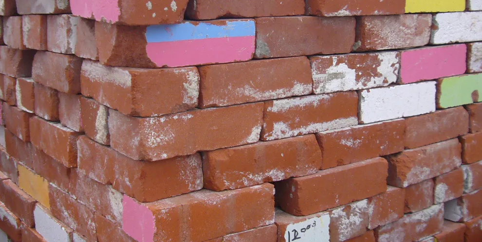 Stacked red bricks with several painted in various colors.