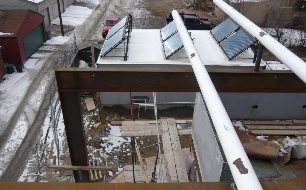 Building under construction featuring flat roof with solar panels and steel structural framing.