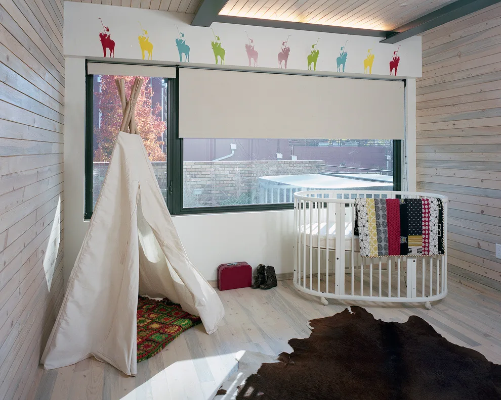 Child's bedroom featuring a white oval crib, teepee, and a window with a roller shade and animal decals above.
