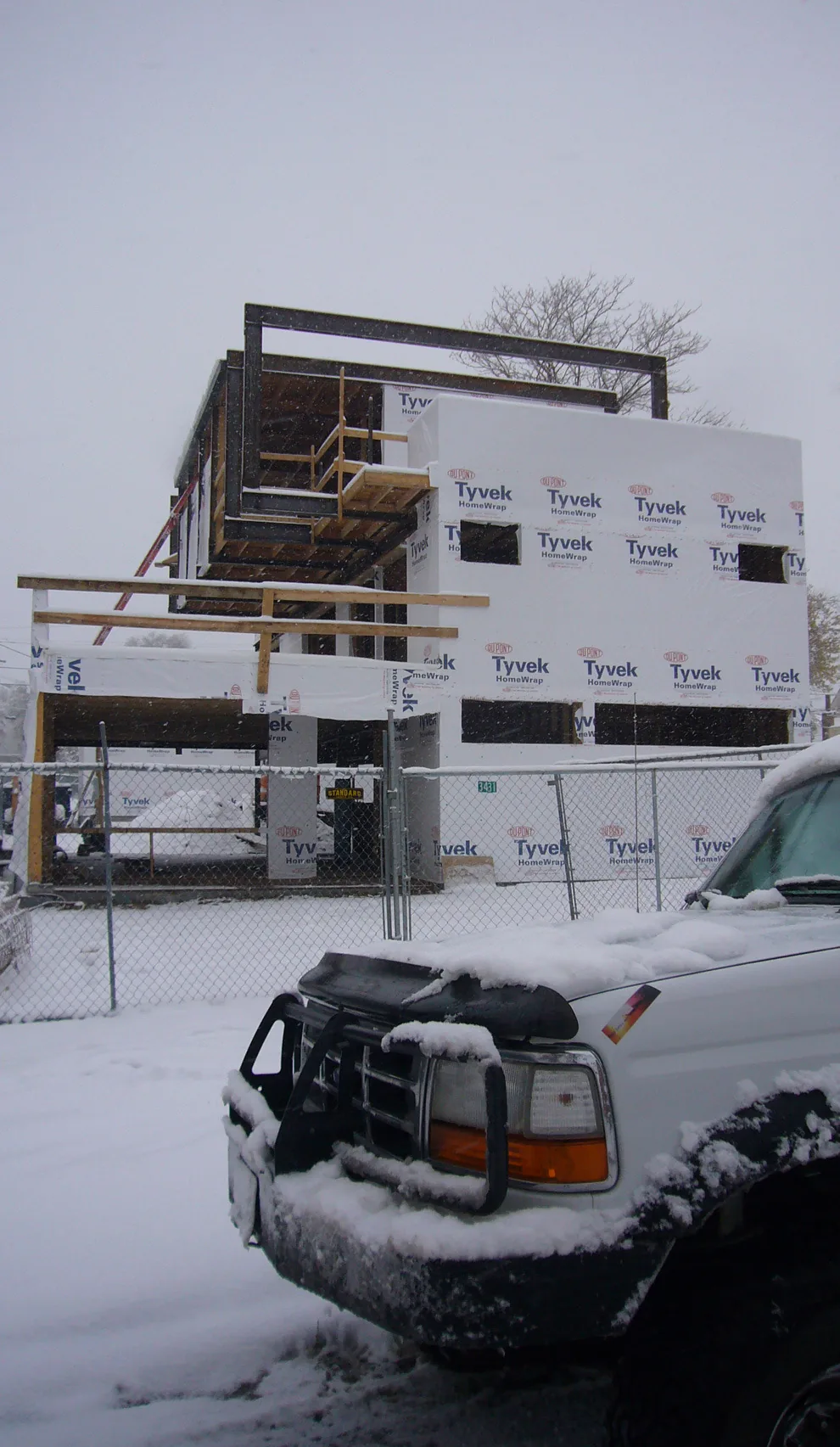 Under construction modern residential structure with timber framing and wrapped exterior in Tyvek HomeWrap.