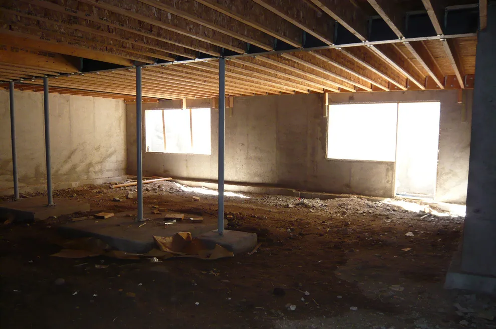 Early construction phase showing exposed ceiling joists and metal columns supporting the structure above.